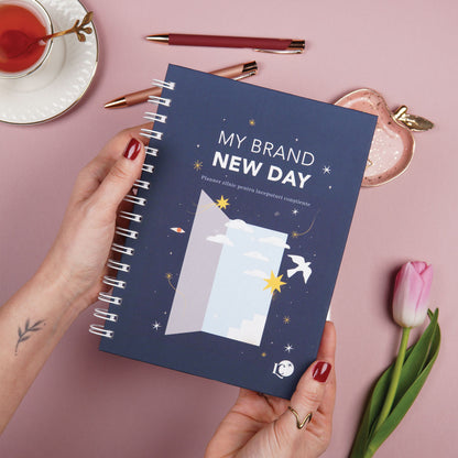 Planner zilnic pentru claritate și direcție tinut in mana